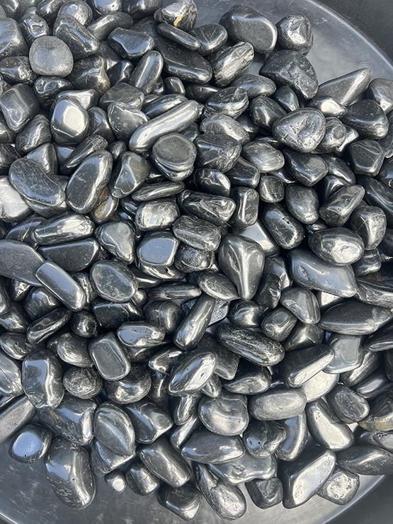 Black polished pebbles close-up texture